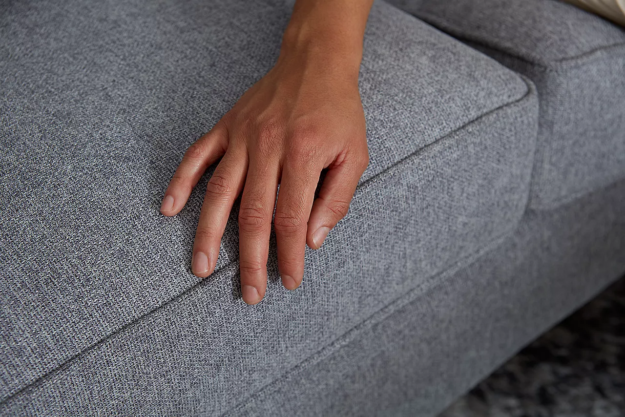 Image of a hand touching a sofa's fabric